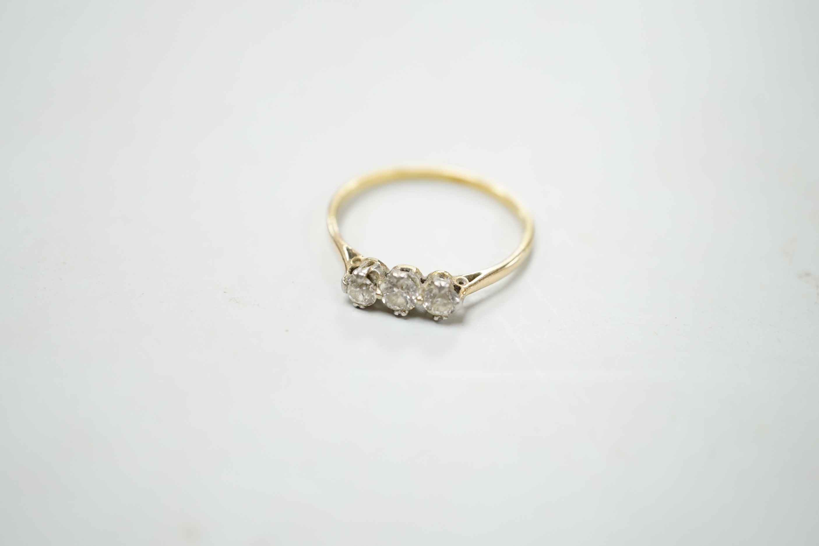 A yellow metal and three stone diamond set ring, size S/T, gross weight 2.1 grams.